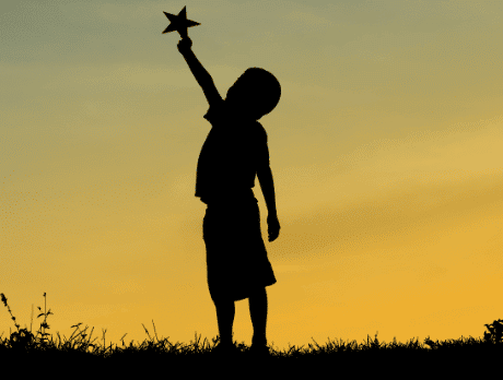 A silhouette of a boy holding up a star