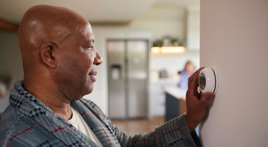 Man turning on thermostat Man turning on thermostat