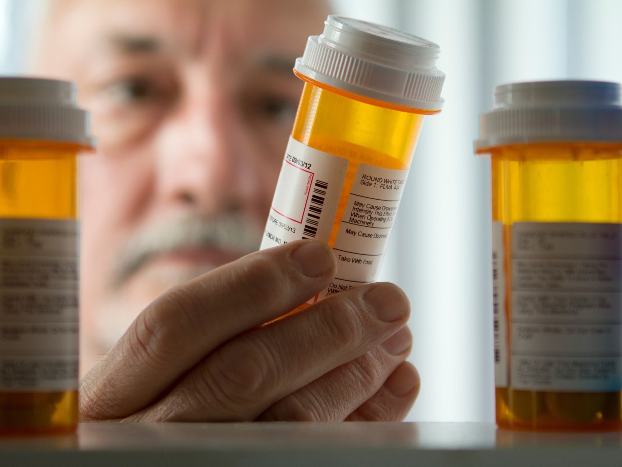 man looking at old medication in medicine cabinet