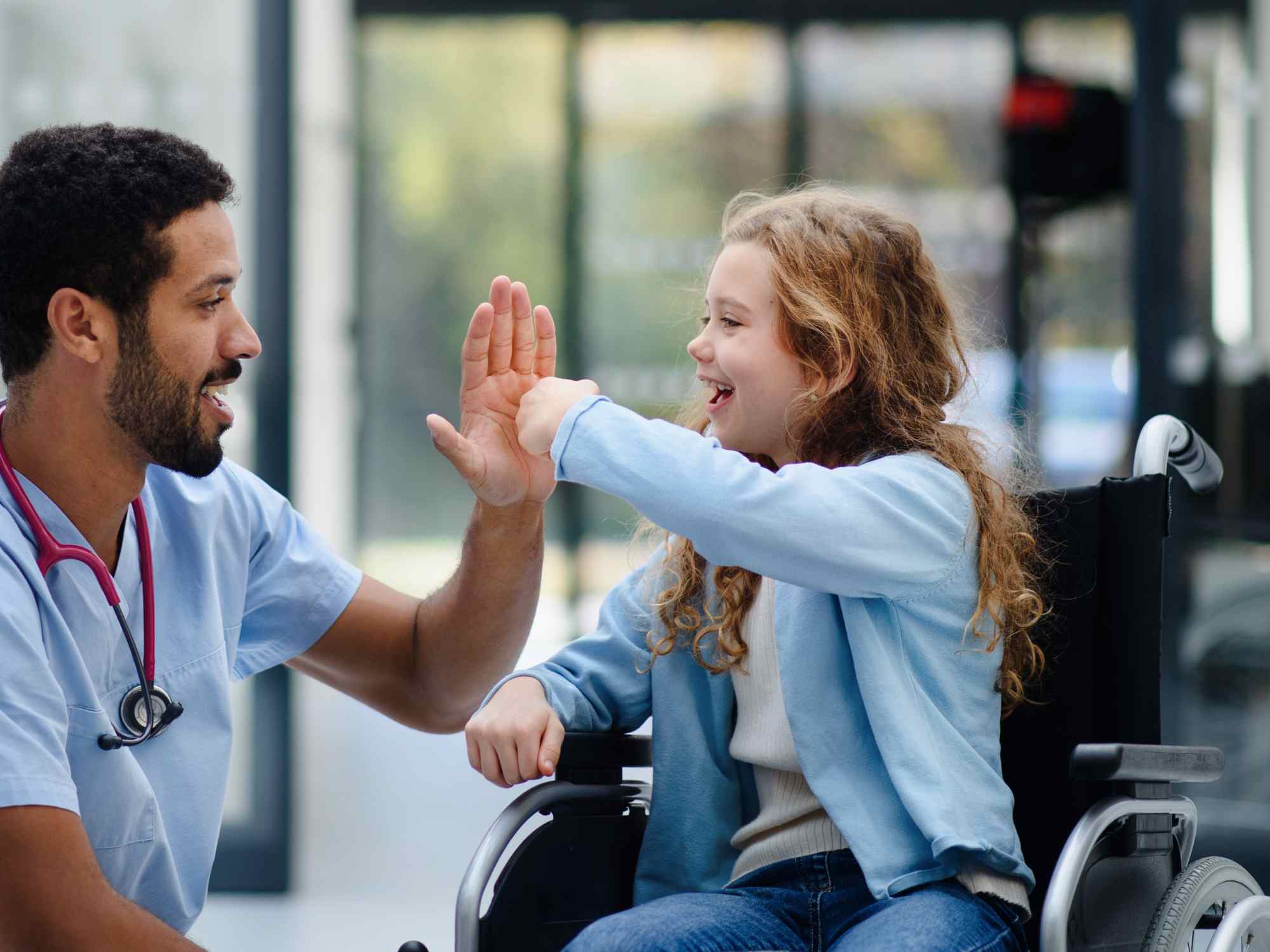 girl in wheelchair high fiving doctor