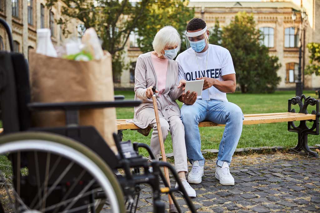 Young man sitting with older woman on park bench