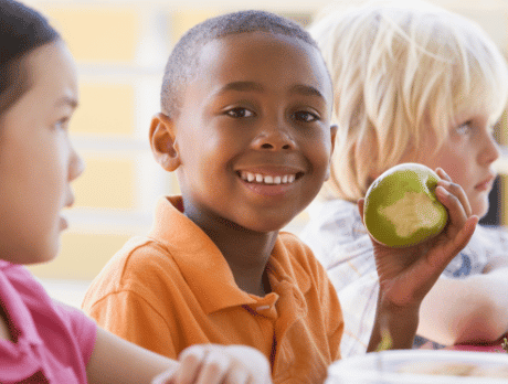 Enfant mangeant une pomme et souriant