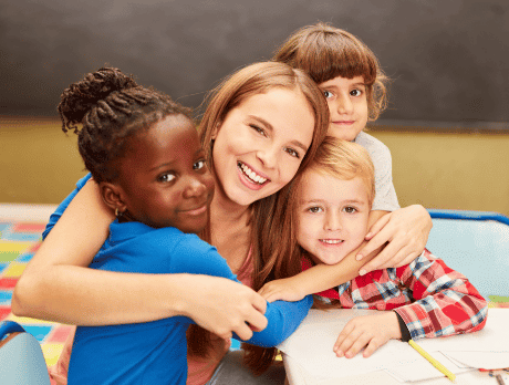 Maestra abrazando a sus alumnos y sonriendo