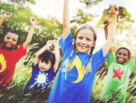 A group of kids with hands raised and smiling