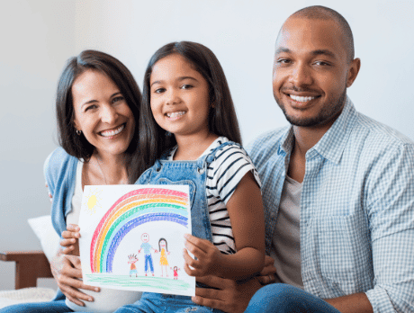 Daughter holding a painting of her family with her parents next to her