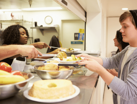 People being served food on plates in a food line