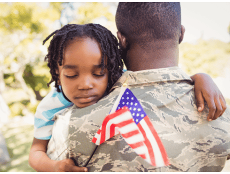 Vétéran étreignant un enfant qui tient un drapeau américain