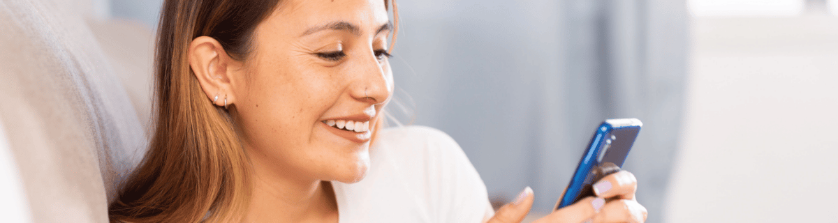 Mujer sonriendo a su teléfono