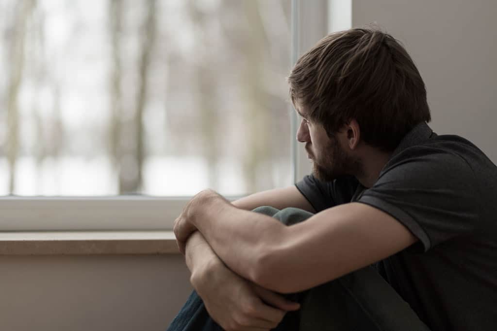 Uomo solo e depresso che guarda fuori dalla finestra