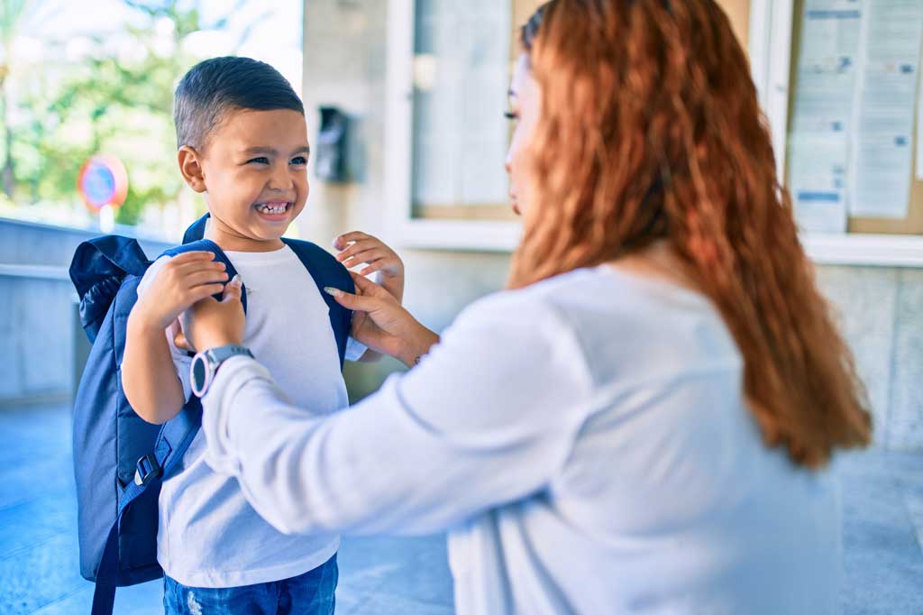 latino young boy putting on his backpack ready for school