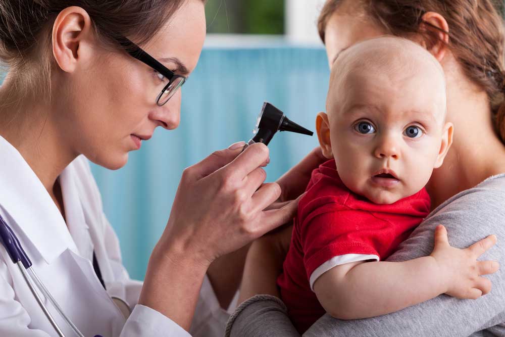 niño recibiendo atención médica mientras el médico mira el oído