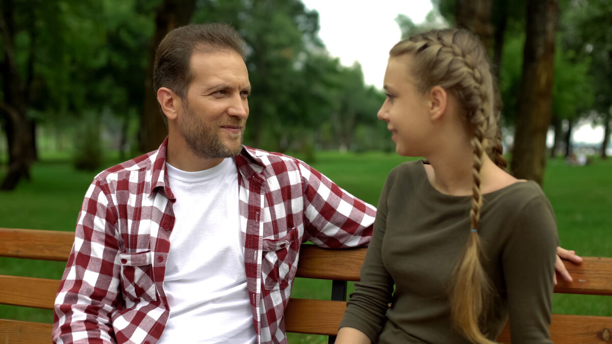 Papa parle à son enfant sur un banc de parc