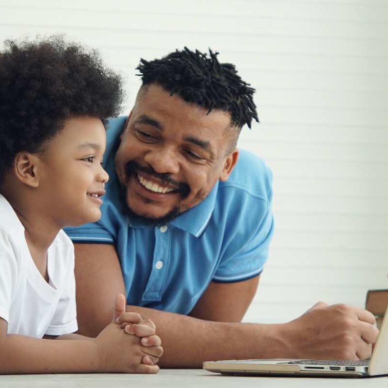 Dad on laptop with child nearby