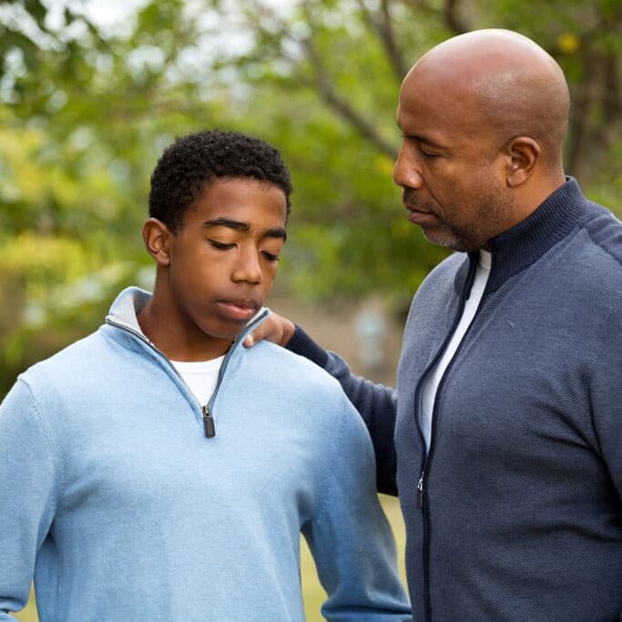 Dad with hand on his son's shoulder providing support