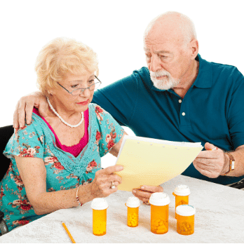 Elderly couple looking worried at medication papers
