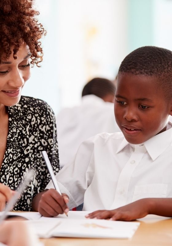 دانش آموز ابتدایی از معلم کمک می گیرد