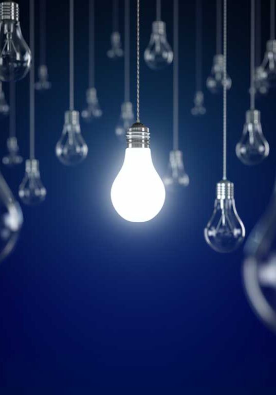 One lit light bulb surrounded by turned off bulbs