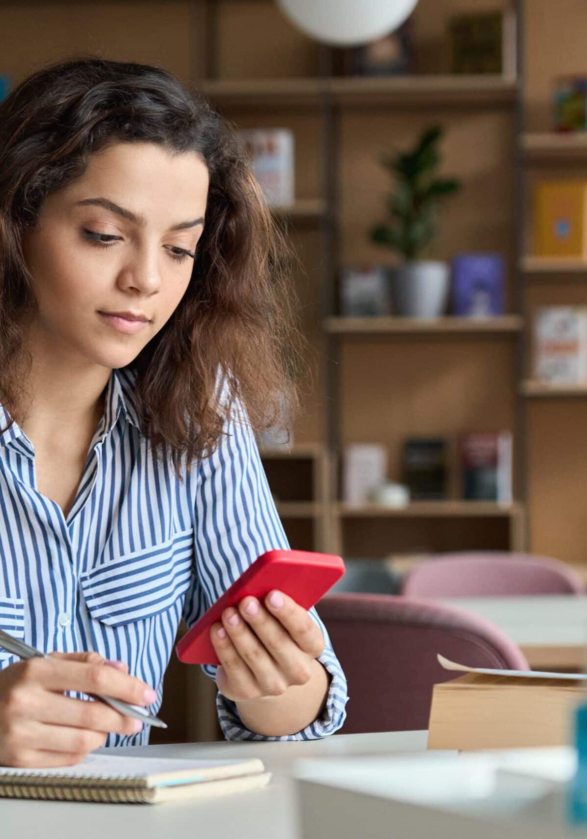 Fille regardant le téléphone avec un bloc-notes et un stylo