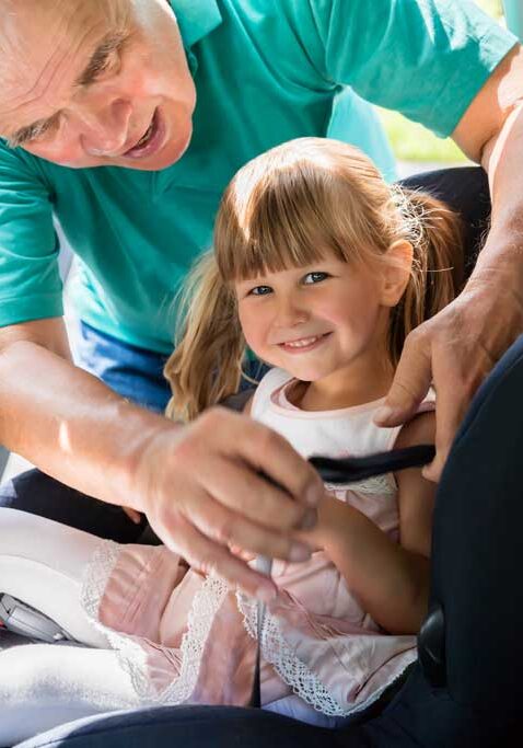 Großeltern, die ihr Kind als Betreuer in den Autositz schnallen