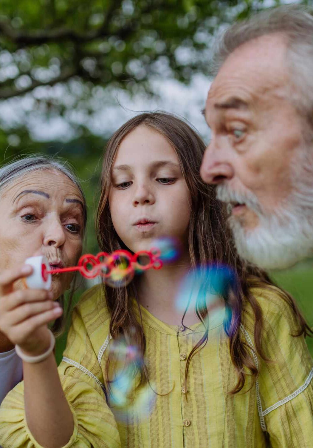 Großeltern pusten Seifenblasen mit Enkelkind