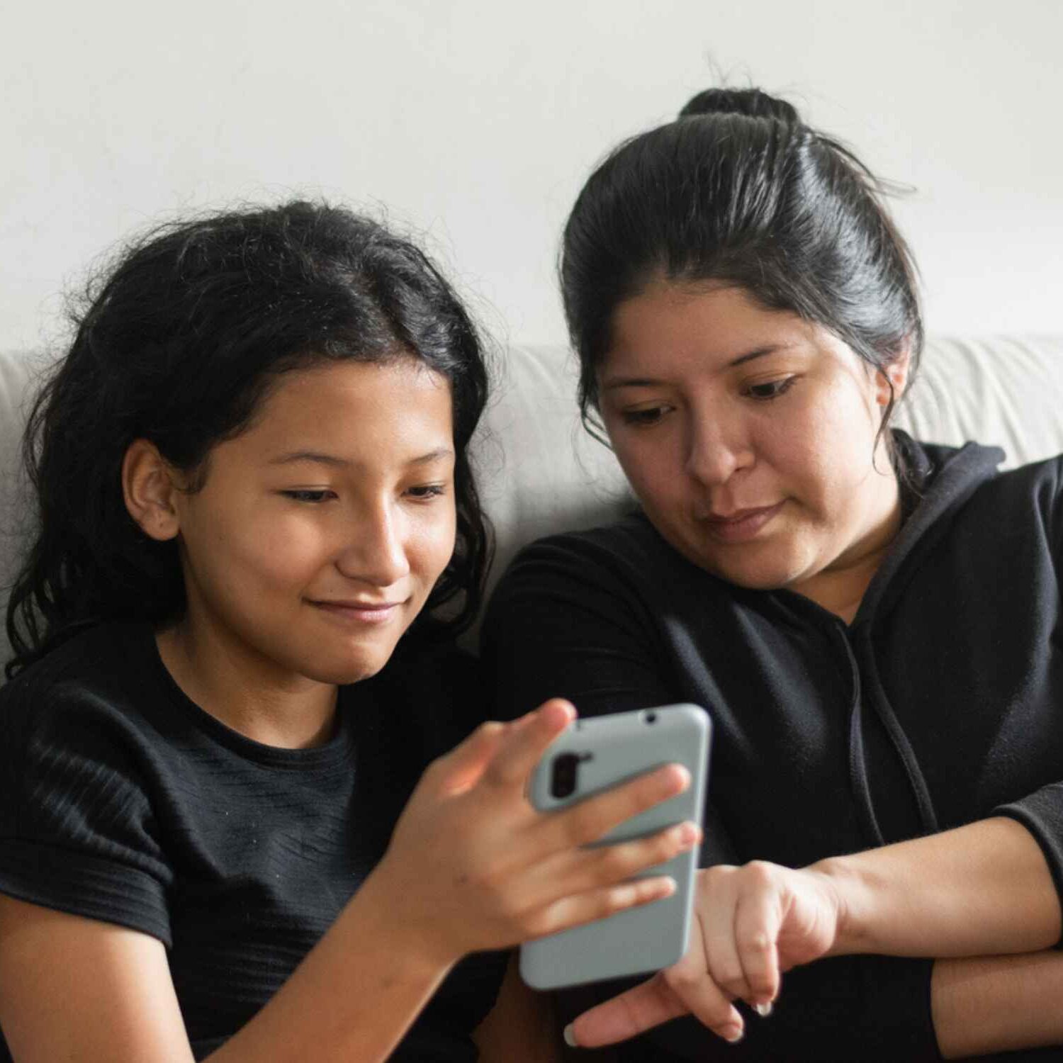 Latina woman and daughter looking on phoen for help