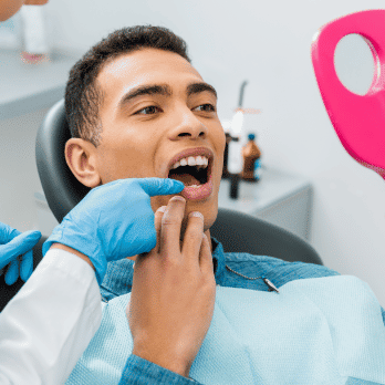 Man at dentist holding a mirror to look at his teeth