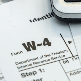 Tax forms and pen laid on top of a laptop