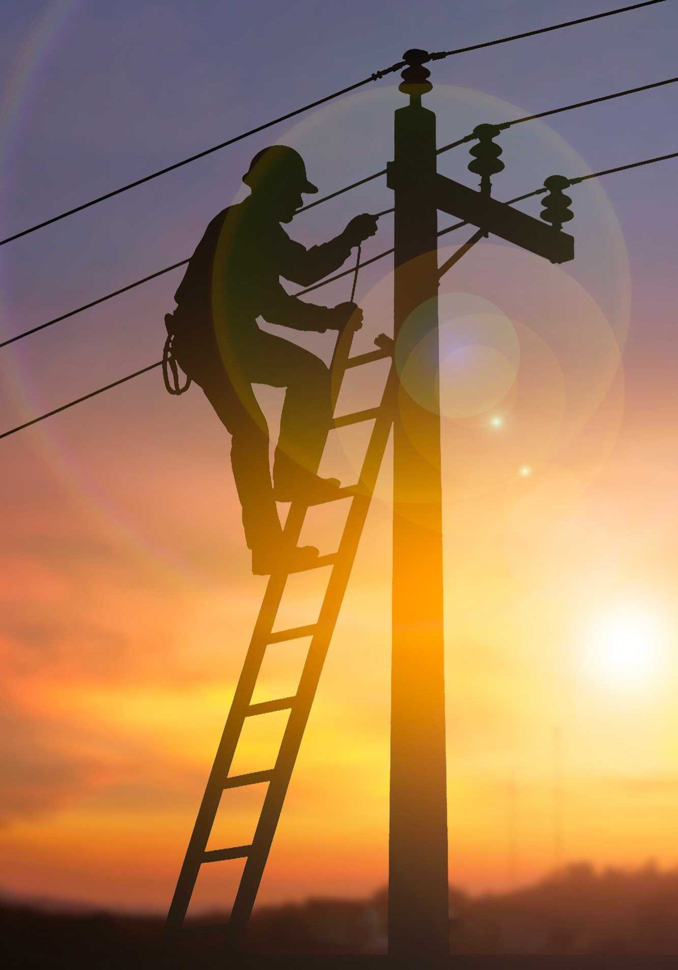 Utility worker on pole and sun behind him