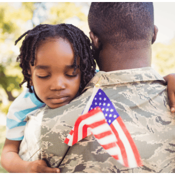 アメリカの国旗を持った子供を抱きしめる退役軍人
