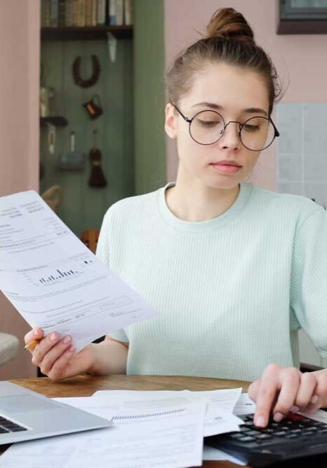 Woman holding utility bill and adding up costs