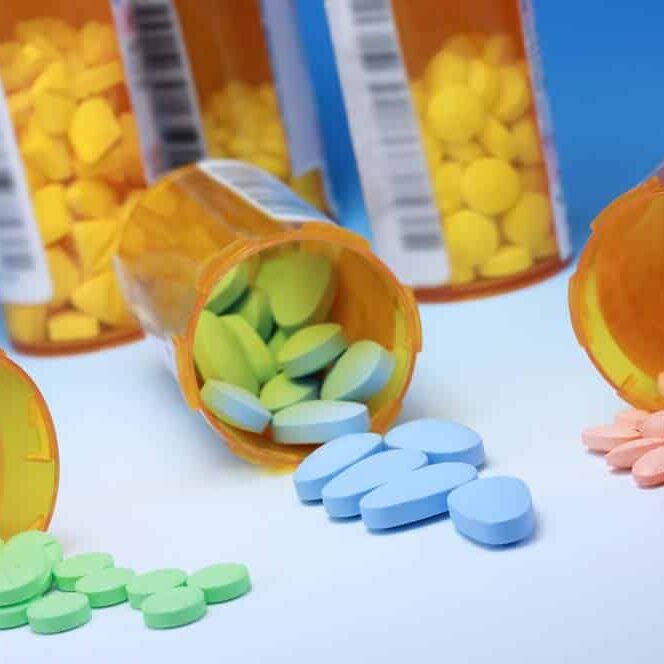 Viên thuốc màu hồng, xanh lam và xanh lục tràn ra khỏi lọ thuốc