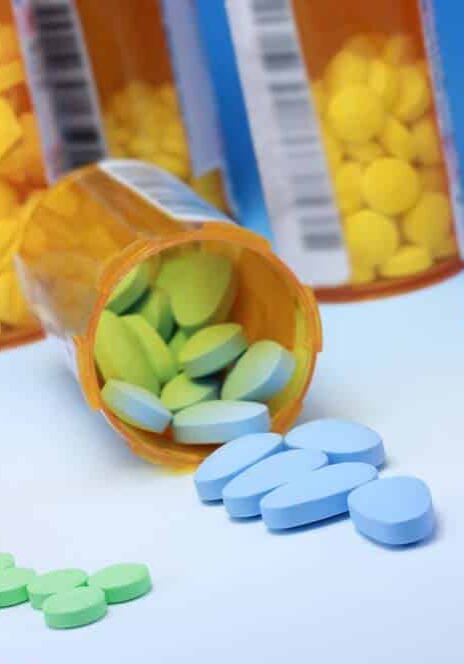 Viên thuốc màu hồng, xanh lam và xanh lục tràn ra khỏi lọ thuốc