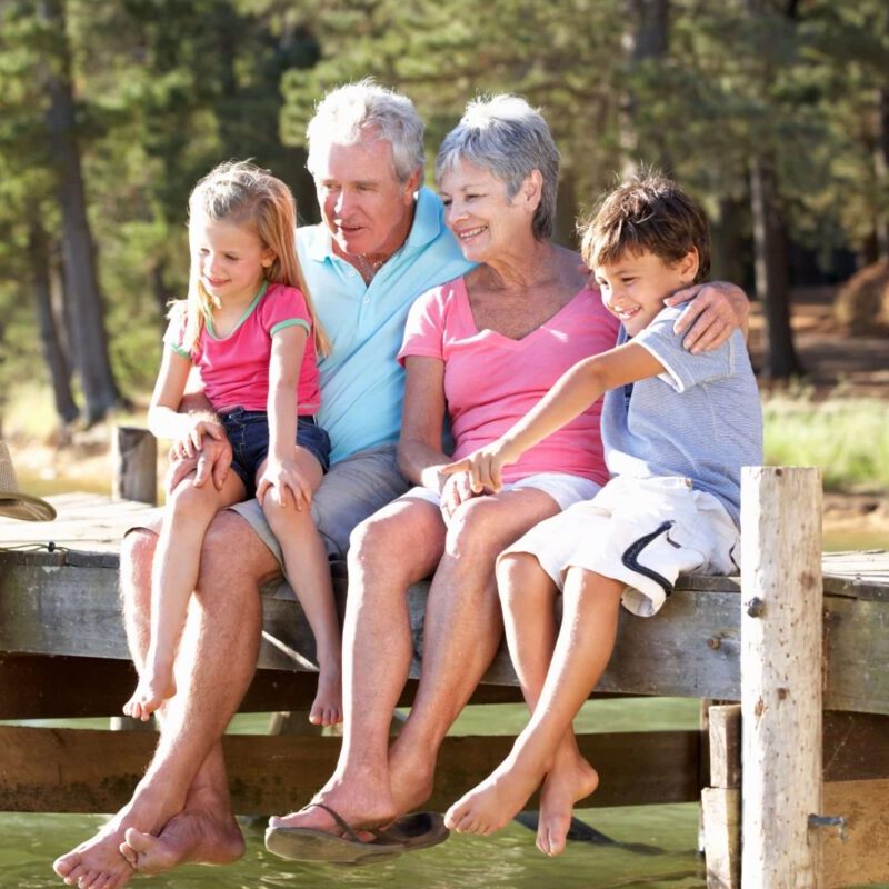 Grandparents sitting with two grandkids on a lake dock